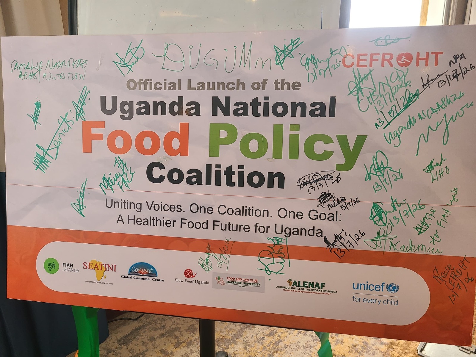 The signed launch banner of the Uganda National Food Policy Coalition reading 'Uniting Voices. One Coalition. One Goal: A Healthier Food Future for Uganda.'