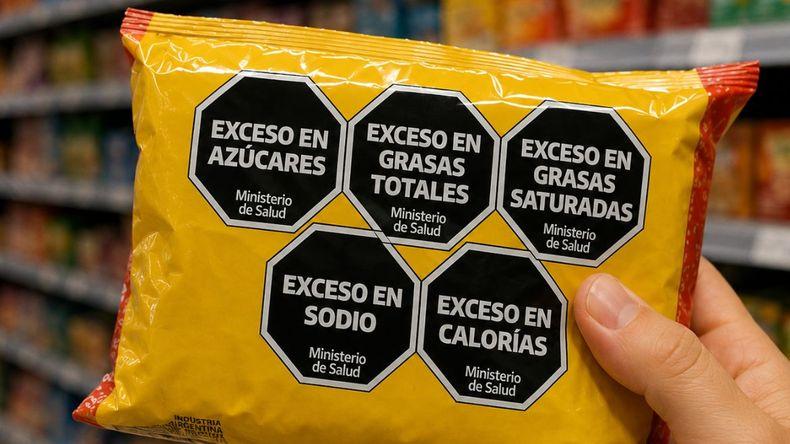 Front-of-pack warning labels in use: a packaged snack bearing several black octagonal labels warning of excess sugar, total and saturated fat, sodium and calories.